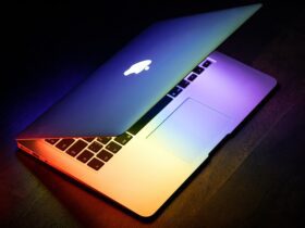 A MacBook lit up in rainbow colors on a wooden surface