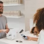 man in grey crew-neck t-shirt smiling to woman on counter