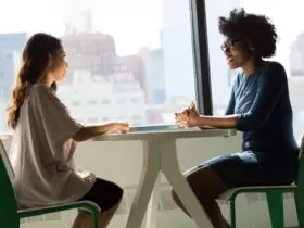 two women sitting beside table and talking